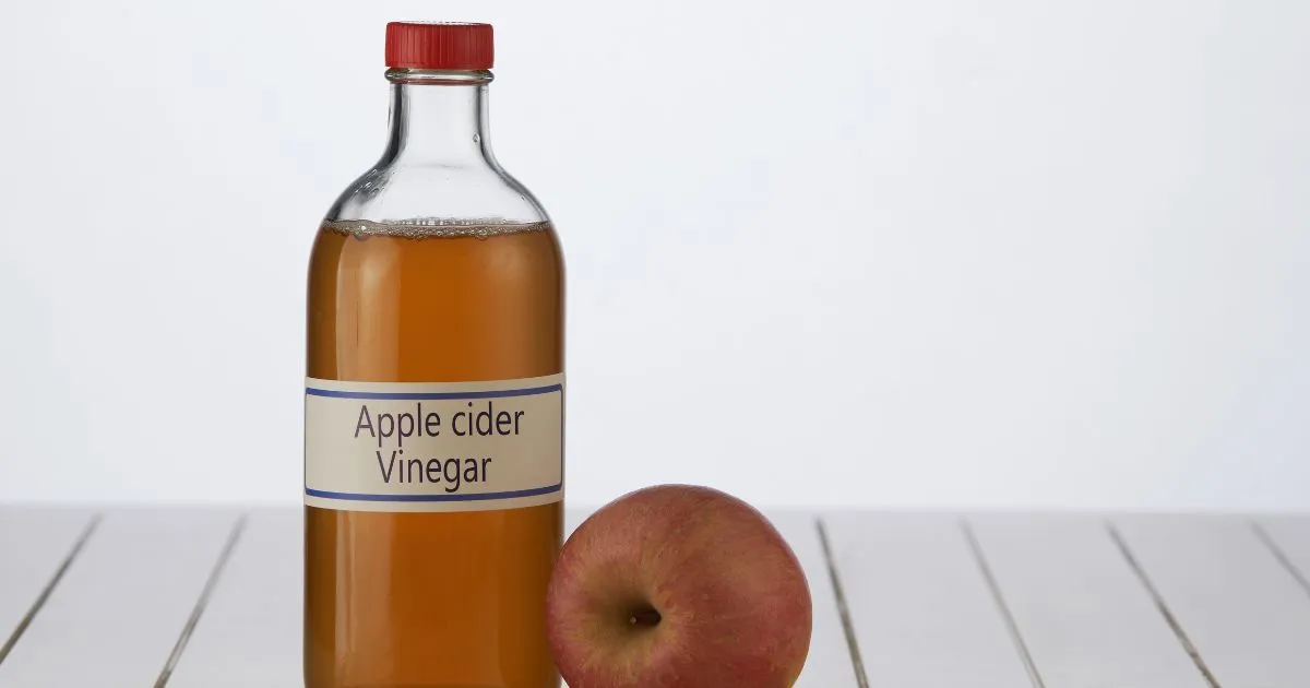 Apple cider vineger and an apple on the table top Apple cider vineger and an apple on the table top