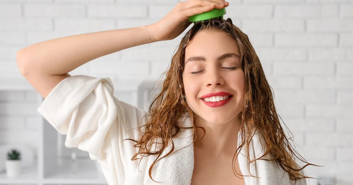 Happy young woman applying scalp scrub Happy young woman applying scalp scrub