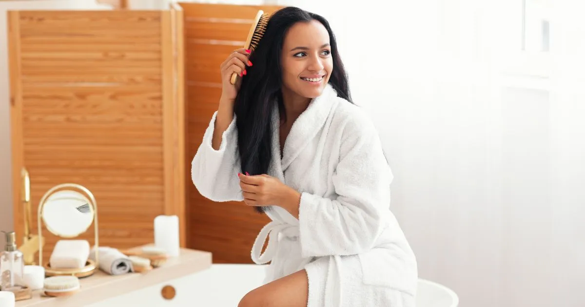 Female Brushing And Detangling Hair Looking Aside Sitting In Bathroom Female Brushing And Detangling Hair Looking Aside Sitting In Bathroom
