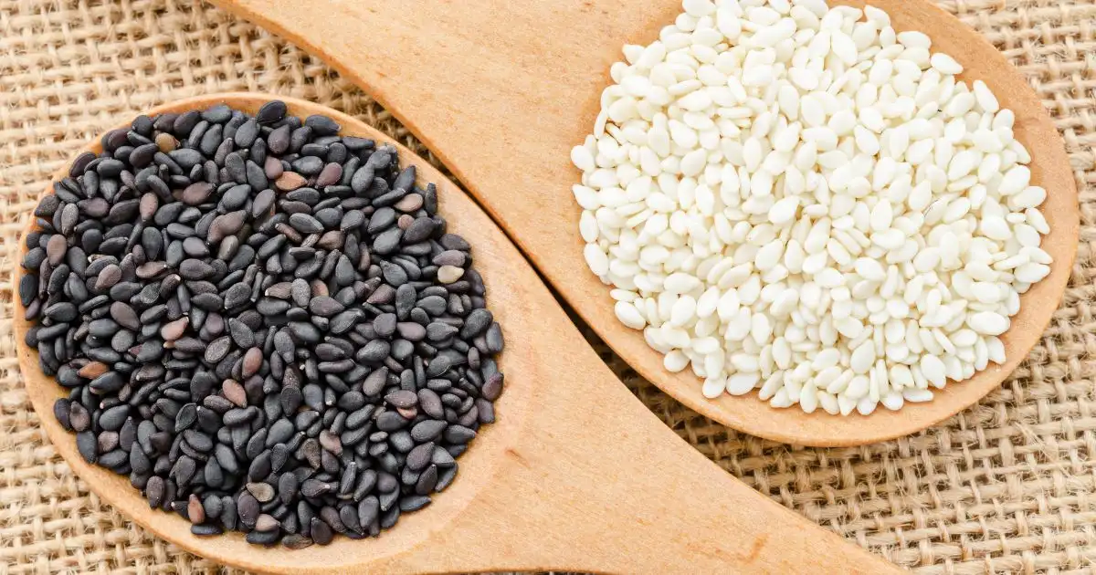 White sesame and black sesame seeds on wooden spoon White sesame and black sesame seeds on wooden spoon