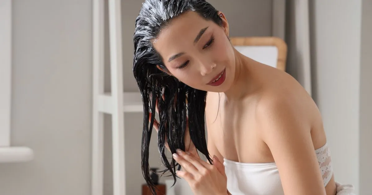 Young Asian Woman Applying Hair Mask in Bathroom Young Asian Woman Applying Hair Mask in Bathroom